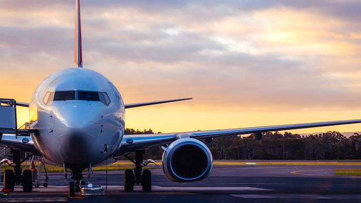 Frente de um avião comercial em uma pista ao anoitecer