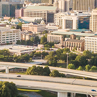 Imagem do centro de Atlanta com uma grande rodovia e veículos em primeiro plano e um aglomerado de edifícios