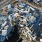 An aerial image of a rubble-scattered neighborhood of white-roofed homes destroyed by a recent hurricane