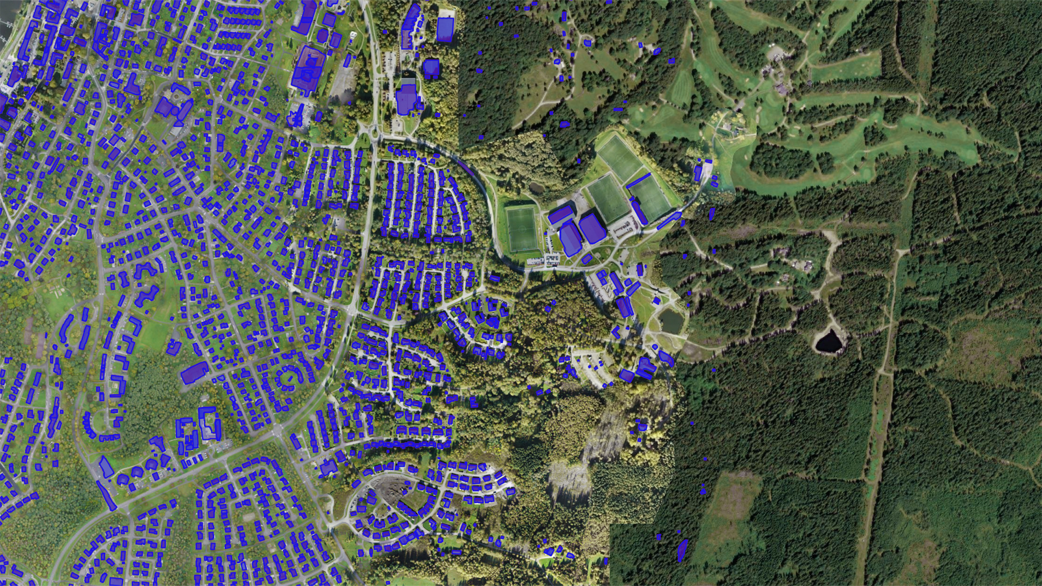 Imagens aéreas de uma área suburbana com uma densa floresta à direita. Os telhados são destacados em azul, indicando potencial para instalações de painéis solares.